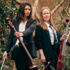 Two women holding cellos looking at the camera