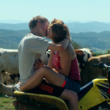 Couple kissing in countryside with cows