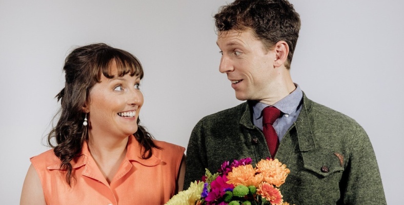 Man and Woman looking at each other. Man holding bunch of flowers